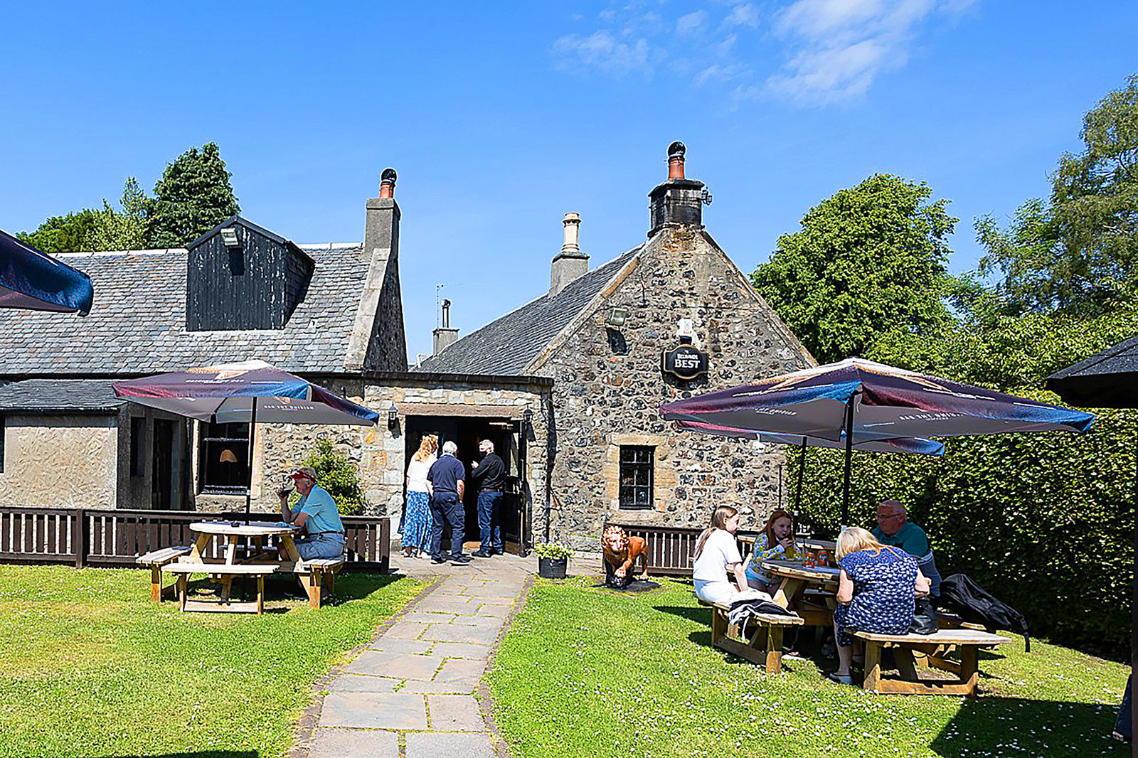 The beer garden at The Wheatsheaf Inn in Symington, with stone walls, picnic tables and guests enjoying a sunny afternoon.
