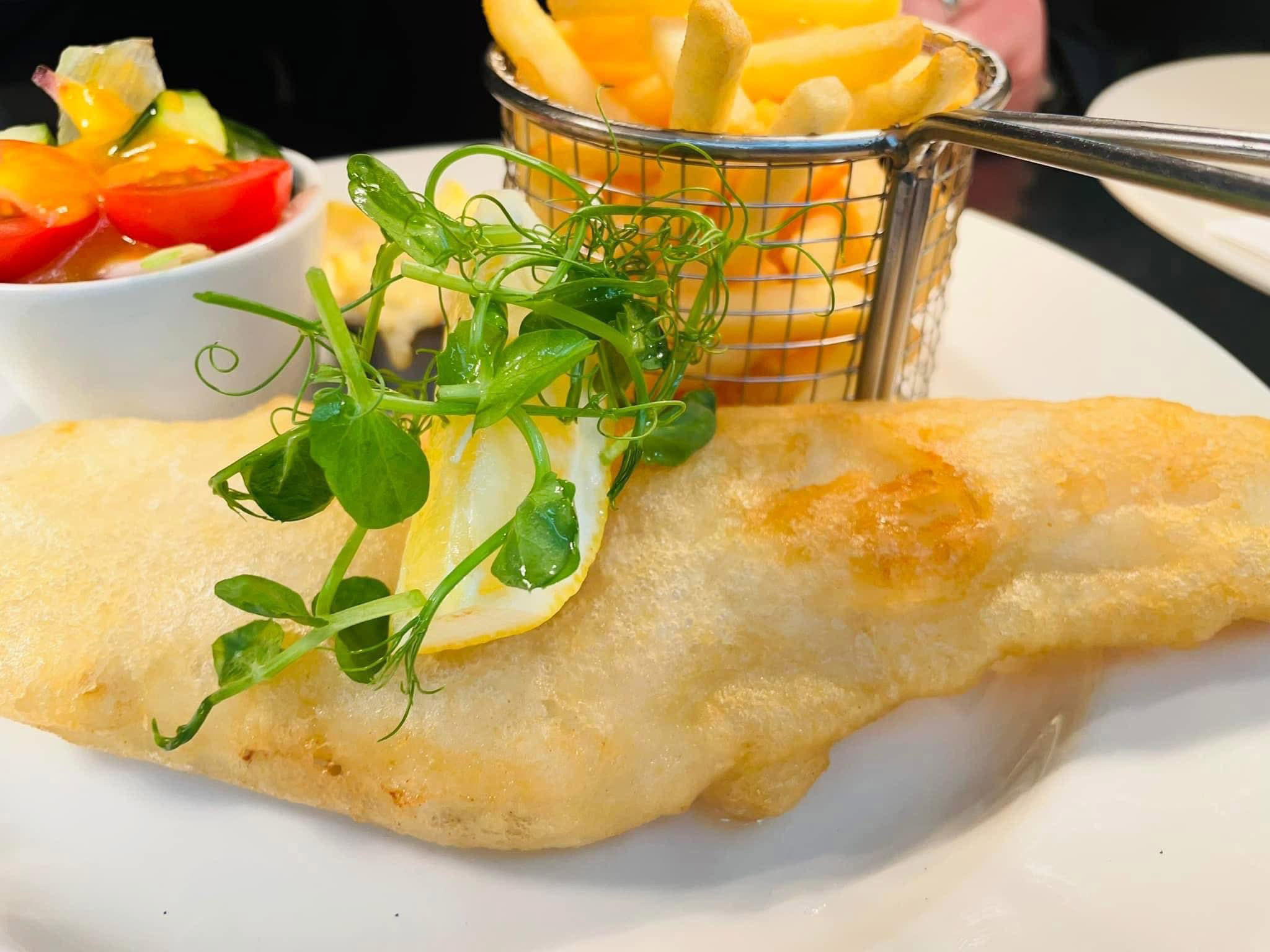 A plated main course of chicken in a creamy sauce, served with rice and a side salad.