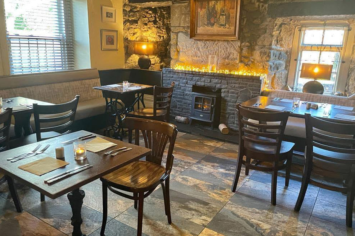 The dining room at The Wheatsheaf Inn, with wood panelling, set tables and a warm country-inn atmosphere.